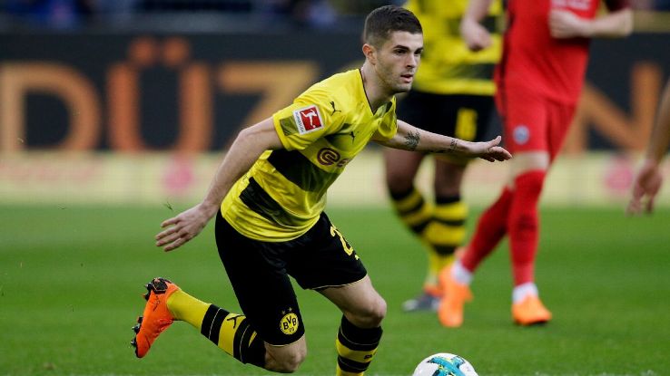 Dortmund's Christian Pulisic dribbles the ball between Eintracht Frankfurt defenders.