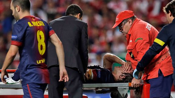 Carles Puyol has his arm held by a team doctor after injuring it in a fall against Benfica