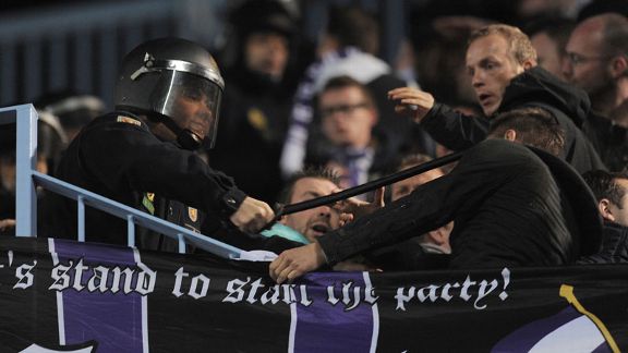 A riot policeman uses his baton on an Anderlecht fan during the Belgian side's 2-2 draw at Malaga