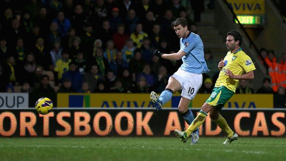 Edin Dzeko shoots on goal as Manchester City net their fourth at Norwich