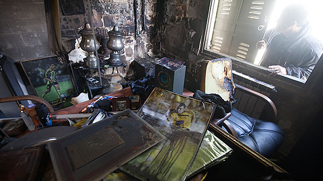 A February 8, 2013 file photo shows a man looking through a window at the damages caused by a fire at the Beitar Jerusalem football club on in Jerusalem. The torching of Beitar Jerusalem's offices by fans angry at the signing of two Muslim players has spa