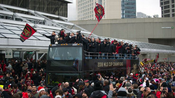 Atlanta United players ride an open-top bus at a parade celebrating the club's MLS Cup win.