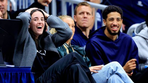 Caitlin Clark y Tyrese Haliburton interactuando durante un partido de baloncesto.