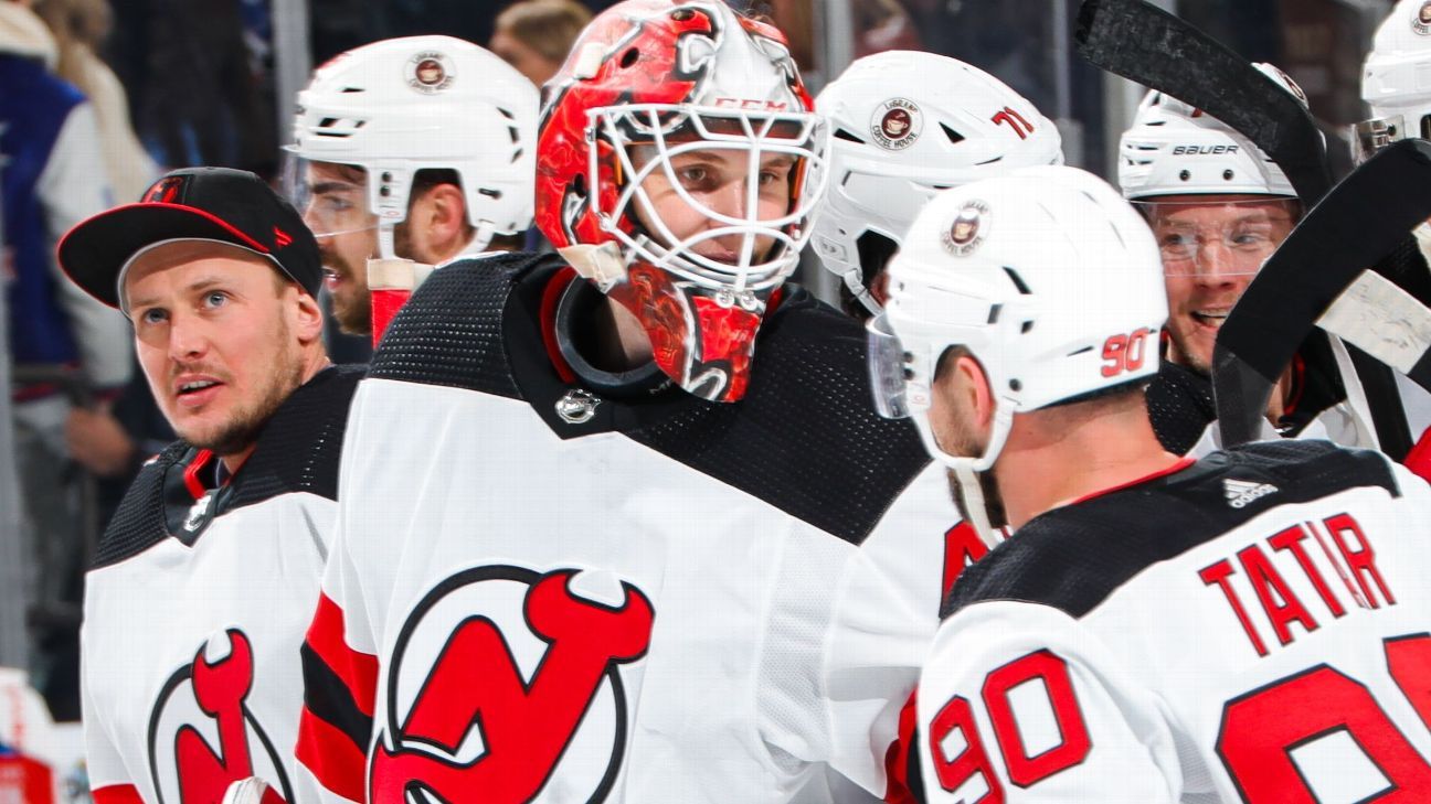 New Jersey Devils goaltender Akira Schmid, back, makes a glove