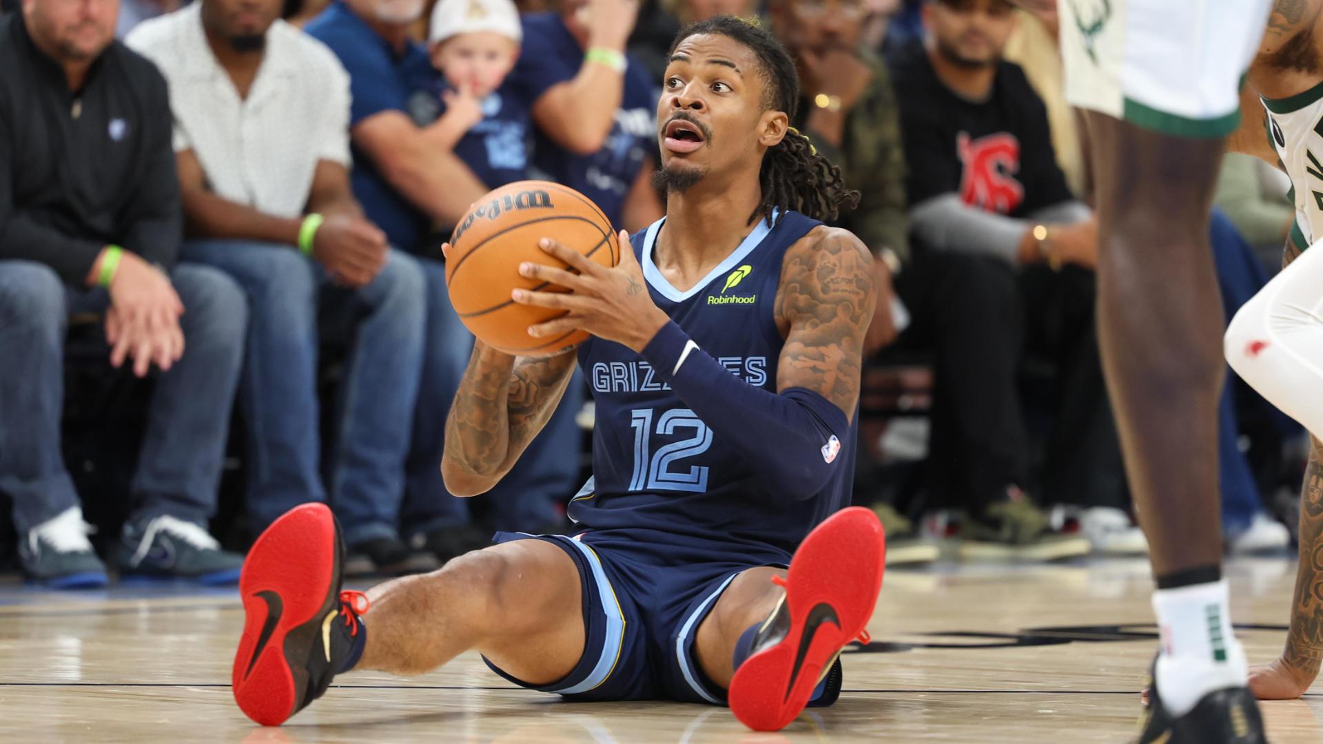 Ja Morant is seated on the court fighting for the basketball and finds an open Santi Aldama for the jam.