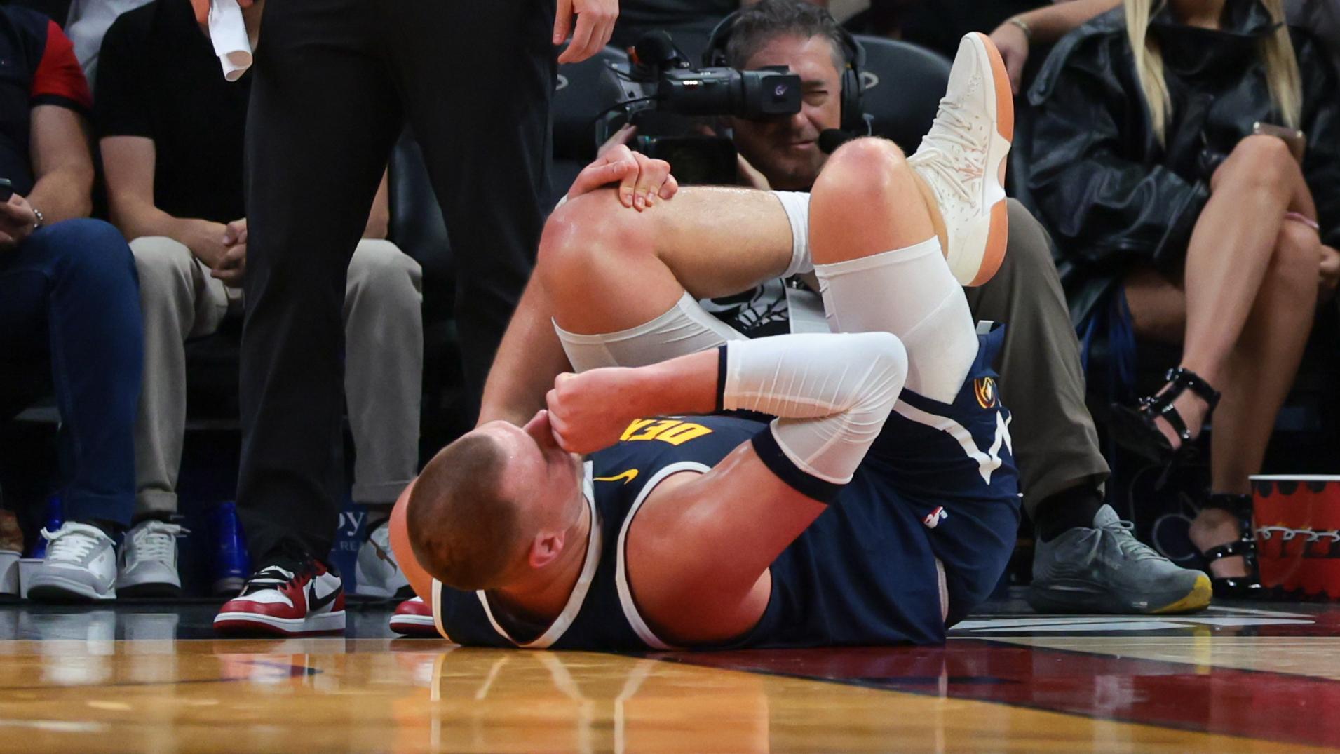 Nikola Jokic goes down hard and limps off to the Nuggets' locker room at the end of the first half vs. the Heat.