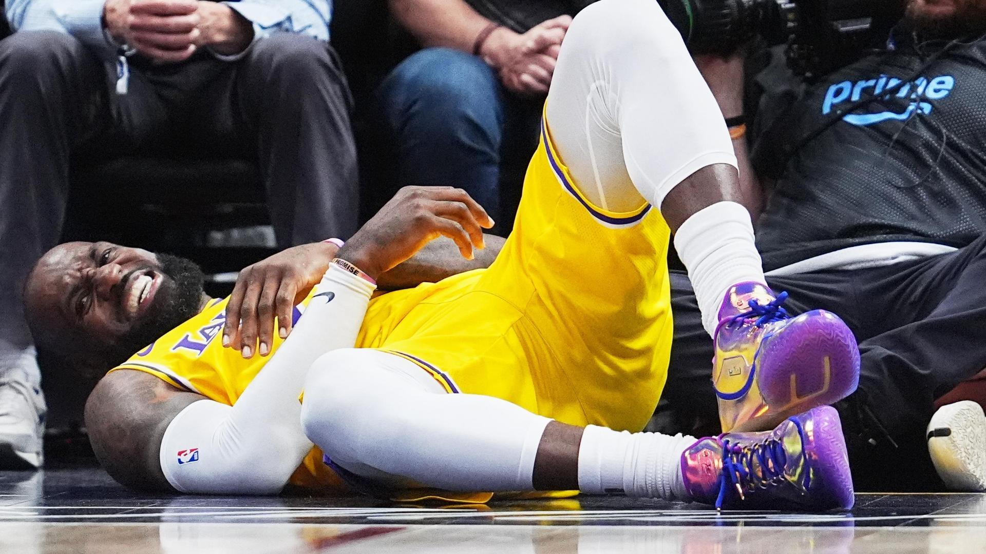 LeBron James takes a bump from Nikola Jokic after scoring, and comes up clutching at his elbow.