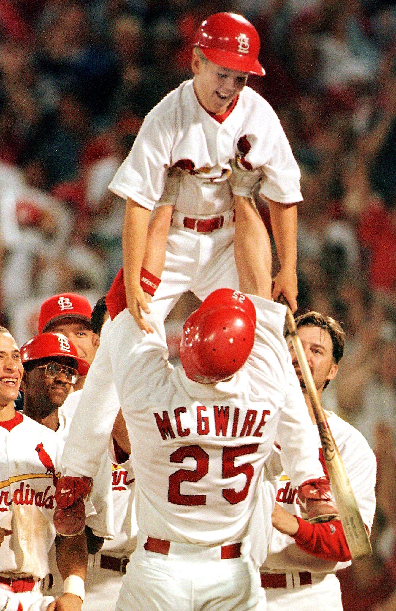 St. Louis Cardinals slugger Mark McGwire lifts his 10-year-old son, Matt, a...
