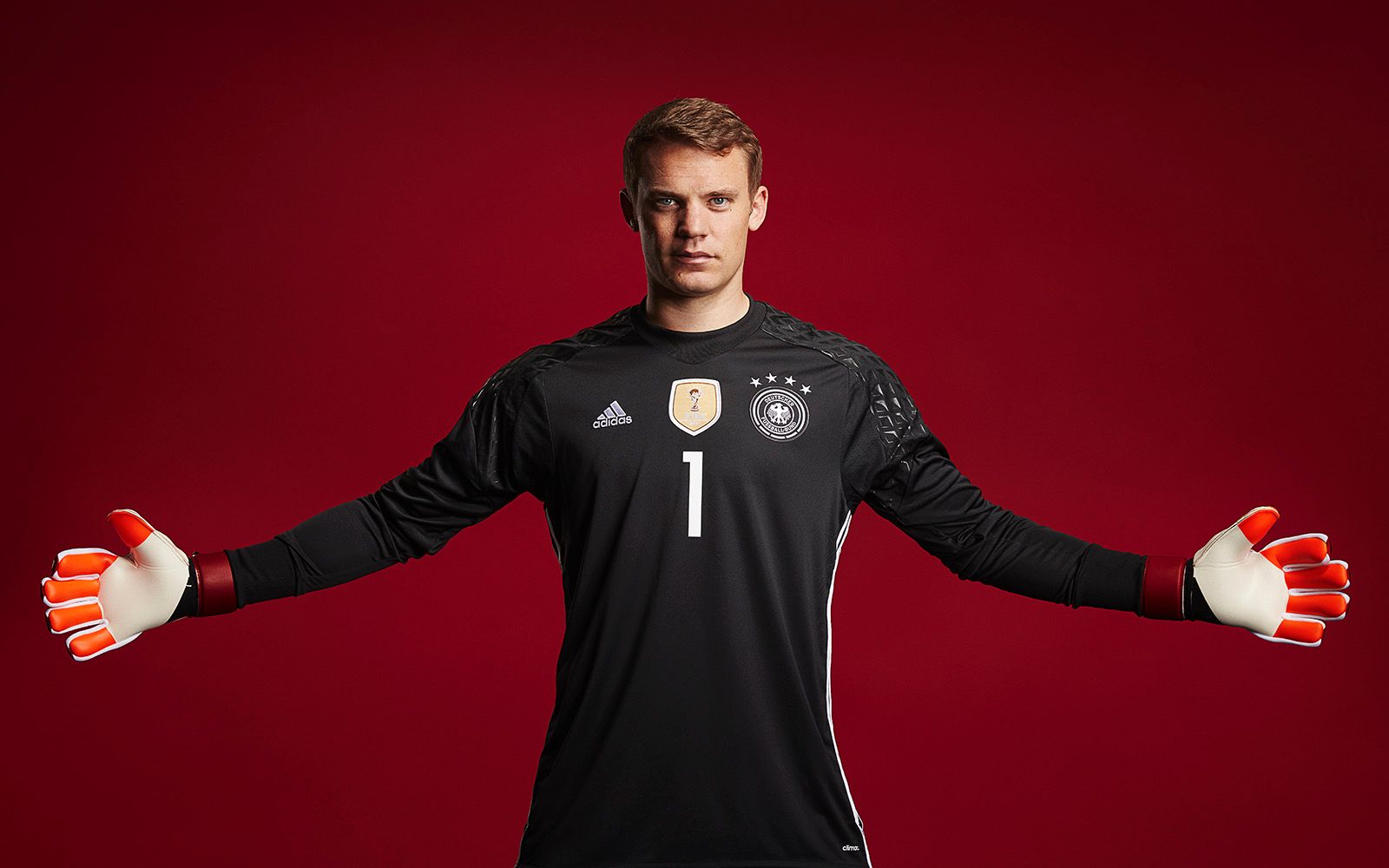  Manuel Neuer, the goalkeeper for Bayern Munich and the German national team, is shown in a black jersey with his arms outstretched.