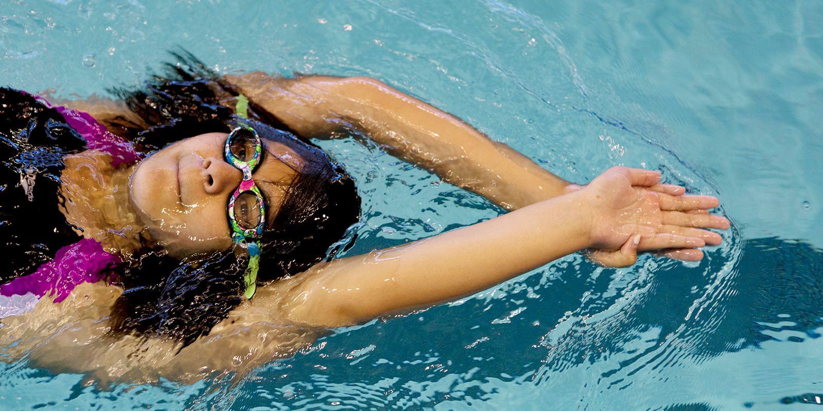 Smiling child in goggles swim, dive in the pool with fun - jump