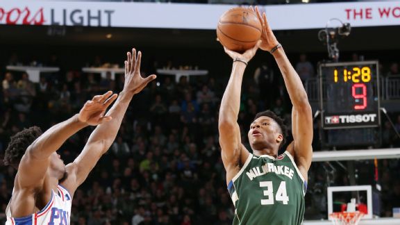 Giannis shoots a three pointer over Joel Embiid