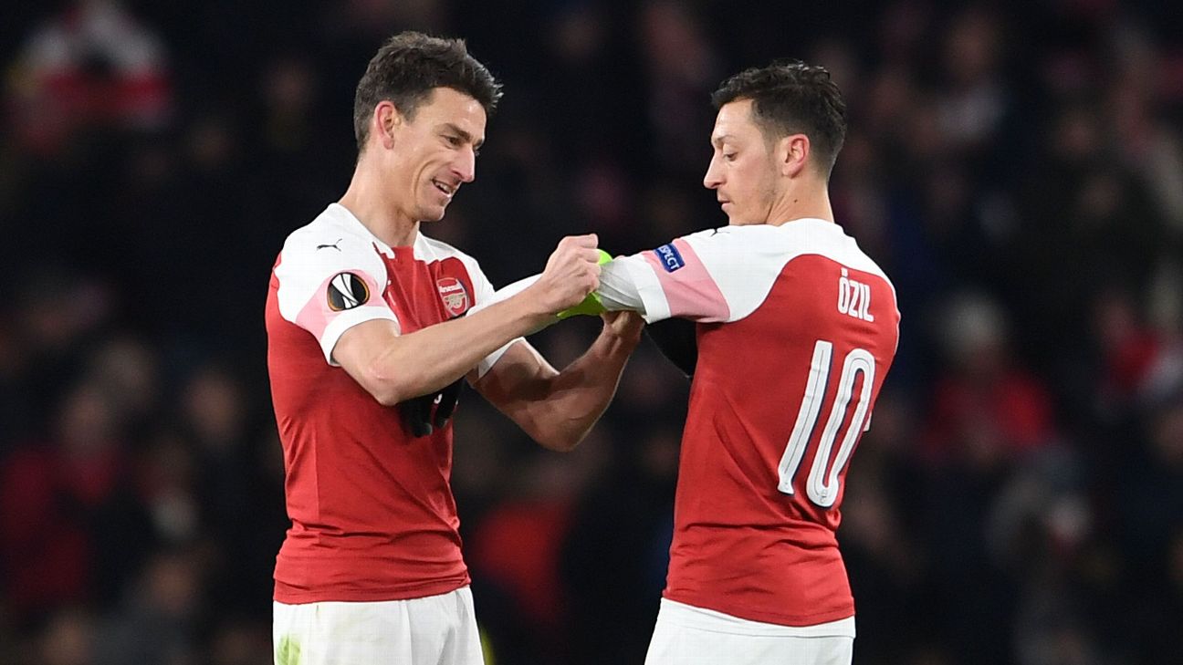 Laurent Koscielny hands the captains armband to Mesut Ozil Laurent Koscielny hands the captains armband to Mesut Ozil