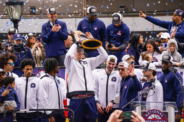 UConn Huskies (UConn Huskies center Donovan Clingan (32) hold up the championship trophy as the team celebrates in front of a large crowd of fans) [600x400]