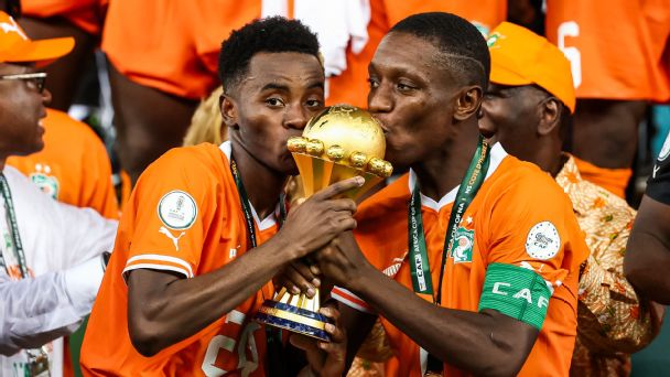 Ivory Coast forwards Max-Alain Gradel (R) and Simon Adingra (L) kiss the Africa Cup of Nations trophy after winning the tournament in 2024.