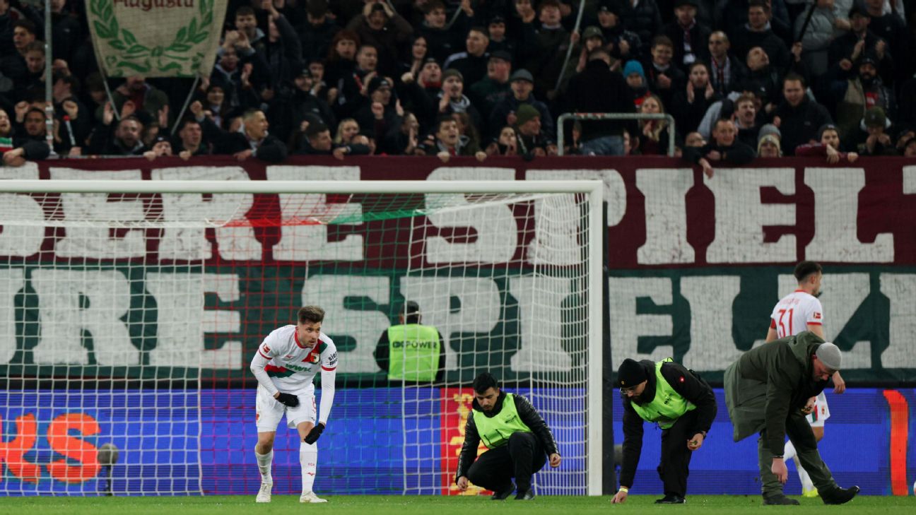 Augsburg players help pick up objects thrown on the pitch by protesting fans during the Bundesliga match against Union Berlin.