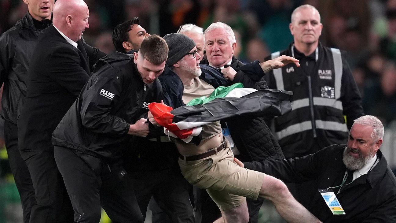 A protestor is escorted off the field by security during the Republic of Ireland's match with Austria in Dublin. — Article image accompanying Protesters interrupt Ireland game in call to boycott Israel match on WagerUp Sports News.